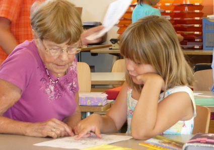 Seniorin unterstützt Schülerin innerhalb der Klasse